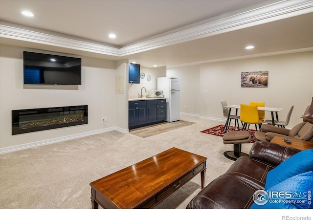 living area with recessed lighting, a glass covered fireplace, light colored carpet, and baseboards