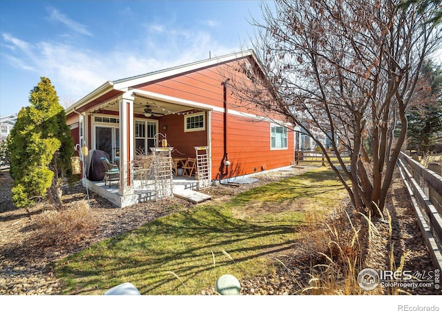 view of side of property featuring a patio, a lawn, a ceiling fan, and fence