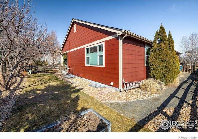 view of side of home with a yard and fence