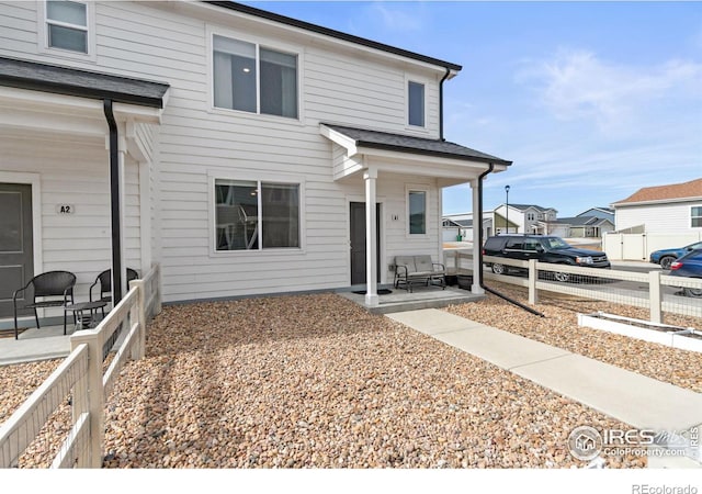 view of front of property featuring a residential view, covered porch, and fence