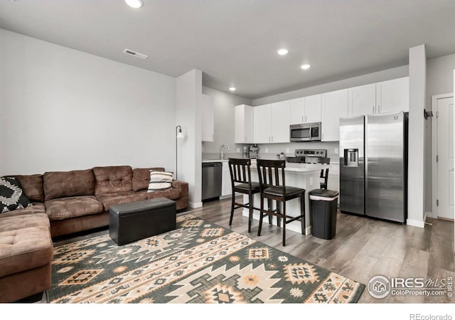 living room featuring recessed lighting, visible vents, and wood finished floors