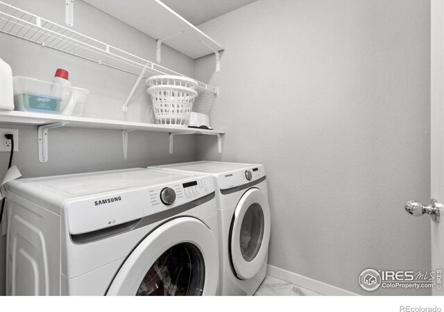 laundry area with laundry area, marble finish floor, baseboards, and separate washer and dryer