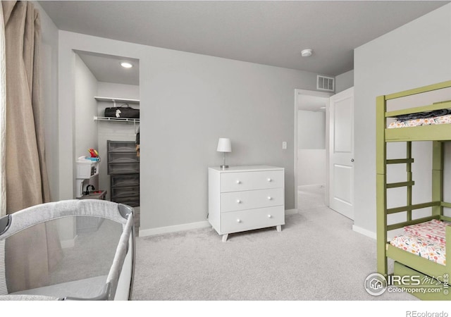 carpeted bedroom with a spacious closet, visible vents, a closet, and baseboards