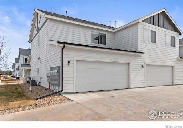 view of front of property featuring an attached garage, cooling unit, board and batten siding, and driveway