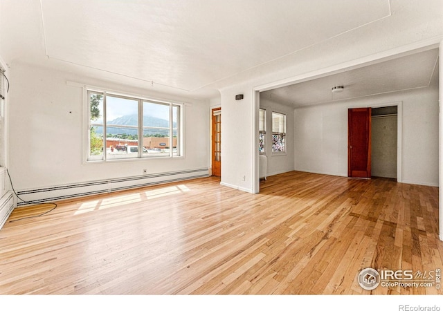 unfurnished room featuring a baseboard heating unit and hardwood / wood-style flooring