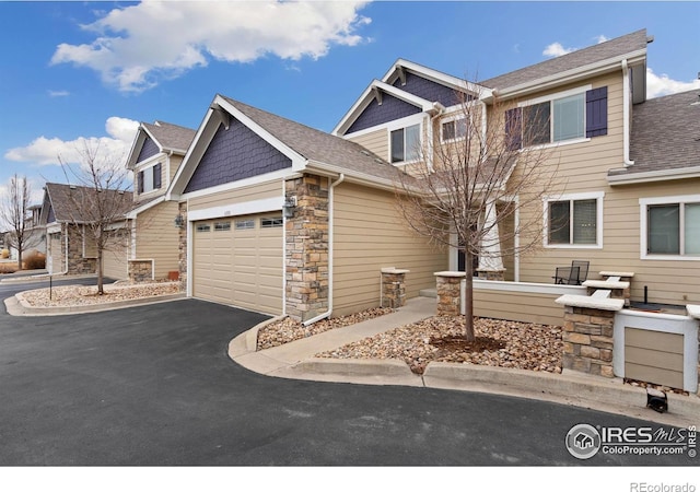 craftsman-style home featuring a garage, stone siding, driveway, and a shingled roof