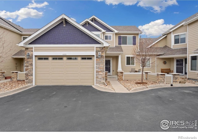 view of front facade with aphalt driveway, stone siding, and a garage