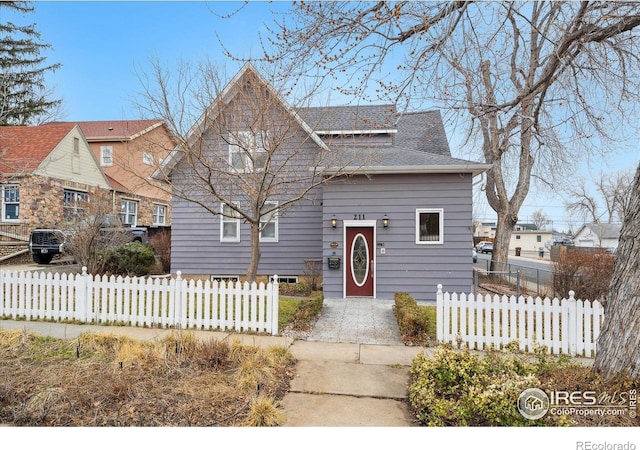 bungalow featuring a fenced front yard and a shingled roof