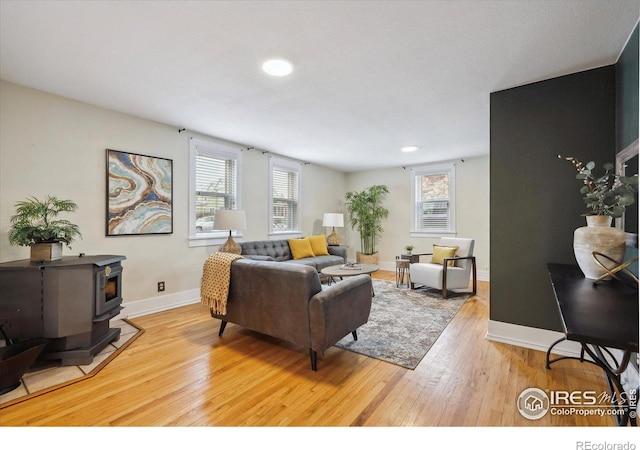 living area with a wood stove, light wood-style flooring, and baseboards