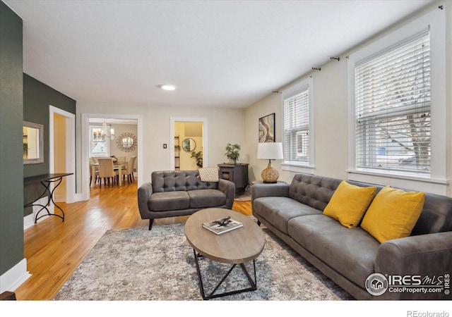 living room with baseboards, an inviting chandelier, and wood finished floors