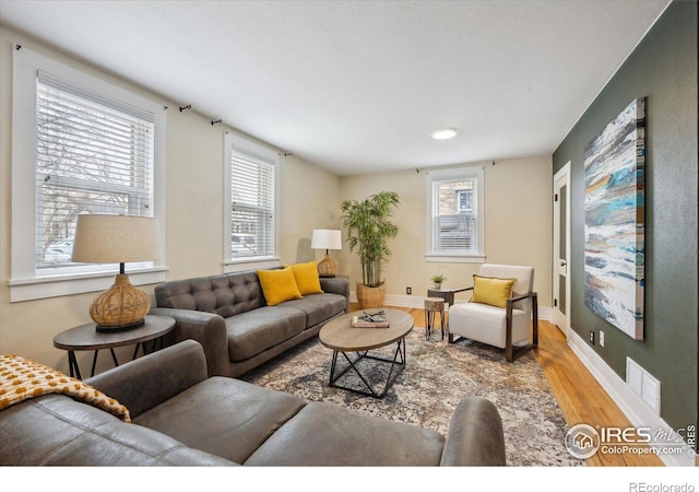 living area with visible vents, baseboards, and wood finished floors