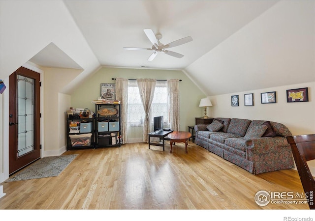 living area featuring vaulted ceiling, baseboards, a ceiling fan, and wood finished floors