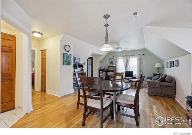 dining area featuring visible vents, light wood-style flooring, baseboards, ceiling fan, and vaulted ceiling