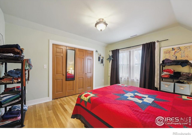 bedroom with vaulted ceiling, light wood-style floors, baseboards, and visible vents