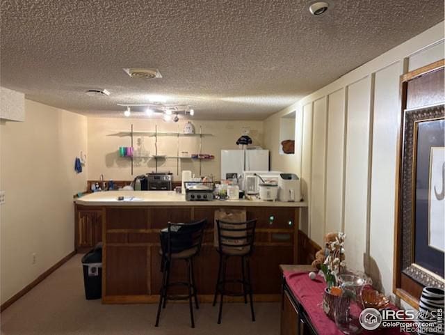 bar with baseboards, a textured ceiling, carpet flooring, and freestanding refrigerator