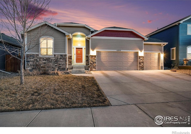 craftsman house with stone siding, an attached garage, and concrete driveway