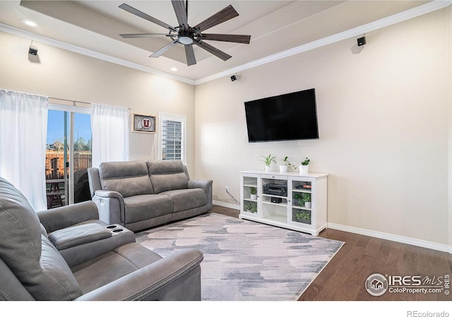 living room featuring a ceiling fan, a raised ceiling, wood finished floors, and baseboards