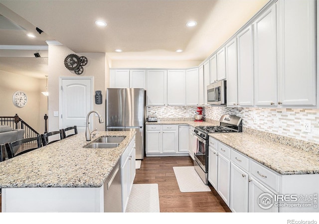 kitchen with backsplash, dark wood finished floors, white cabinets, stainless steel appliances, and a sink