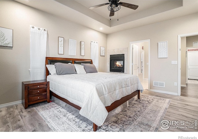 bedroom with visible vents, a raised ceiling, and wood finished floors