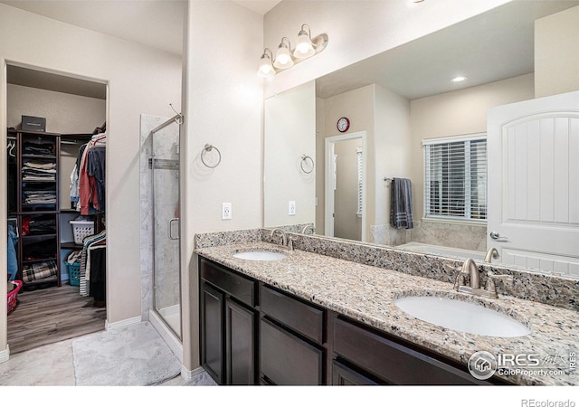 full bathroom with a sink, a shower stall, a spacious closet, and double vanity