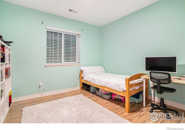 bedroom with visible vents, baseboards, and wood finished floors