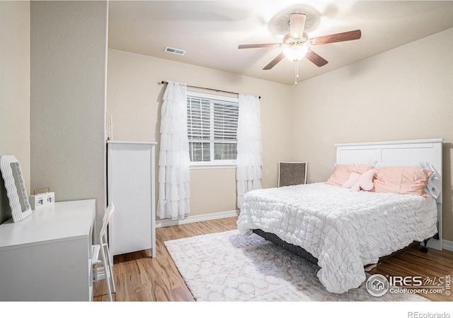 bedroom with a ceiling fan, visible vents, light wood finished floors, and baseboards