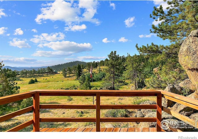 deck featuring a mountain view and a view of trees