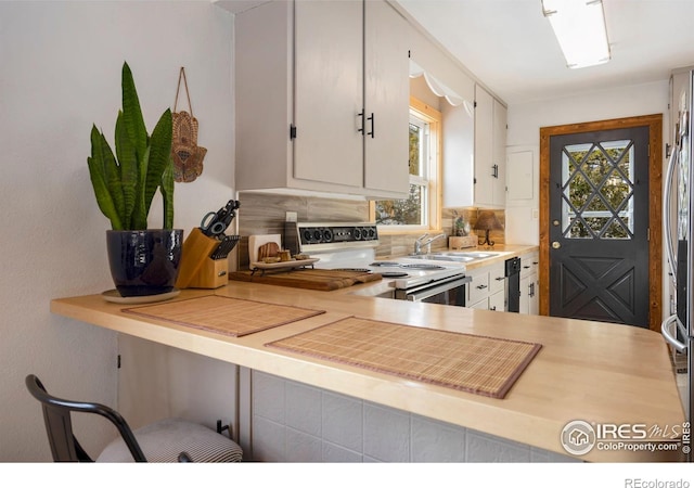 kitchen featuring tasteful backsplash, light countertops, white electric range oven, white cabinets, and a sink