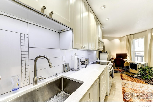 kitchen with white appliances, recessed lighting, and a sink