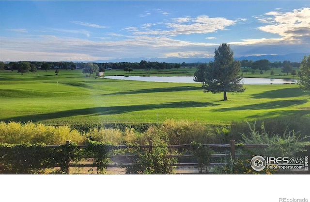 view of home's community with a lawn, view of golf course, and a water view