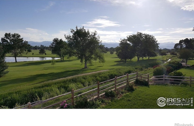 view of yard with a rural view, fence, and a water and mountain view