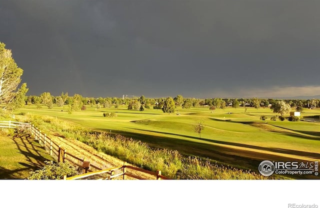 view of property's community with a yard, view of golf course, and fence