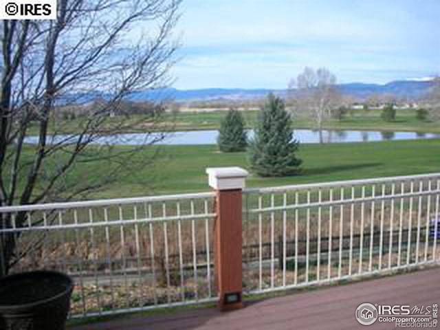 view of gate with a lawn, fence, and a water view