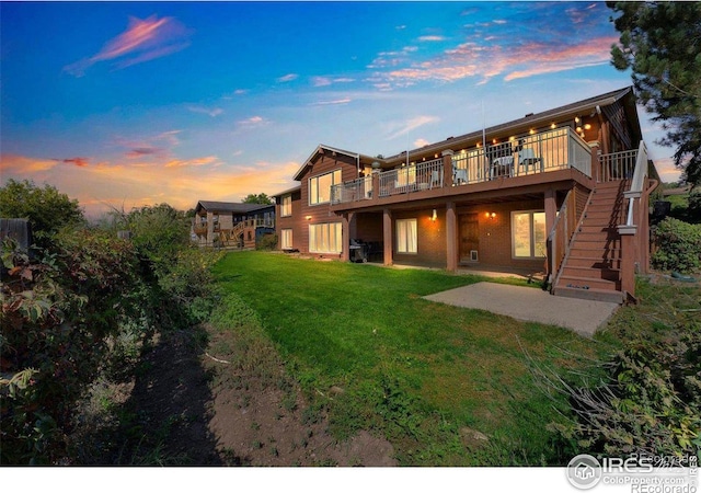 back of house featuring stairway, a lawn, a wooden deck, and a patio