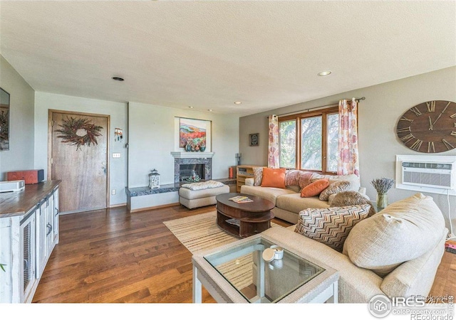 living area featuring an AC wall unit, recessed lighting, a fireplace, wood finished floors, and a textured ceiling