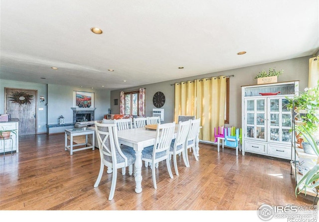 dining area featuring recessed lighting, a fireplace, and wood finished floors