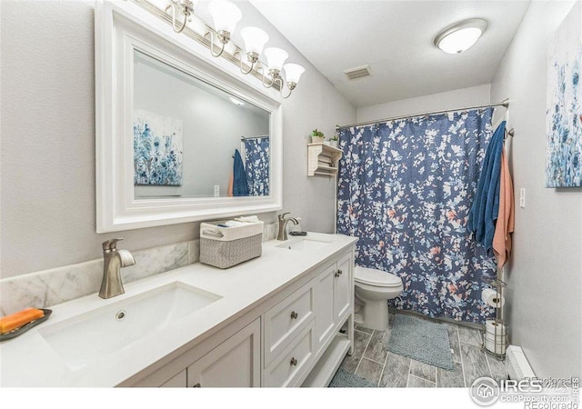 bathroom with double vanity, toilet, visible vents, and a sink