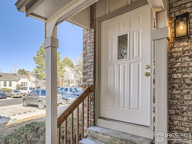 doorway to property featuring a residential view, brick siding, uncovered parking, and a balcony