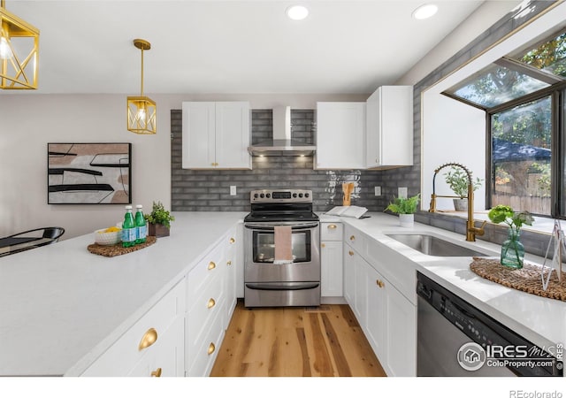 kitchen with a sink, tasteful backsplash, stainless steel appliances, wall chimney exhaust hood, and light countertops