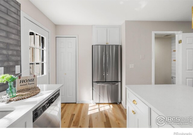 kitchen with white cabinetry, light countertops, light wood finished floors, and appliances with stainless steel finishes