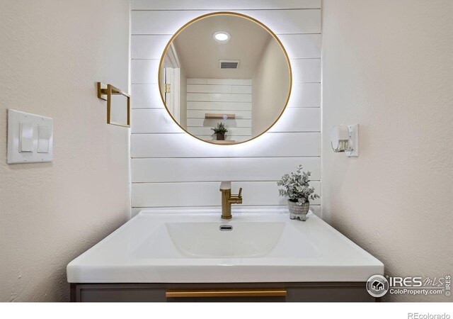 bathroom with vanity, a textured wall, and visible vents