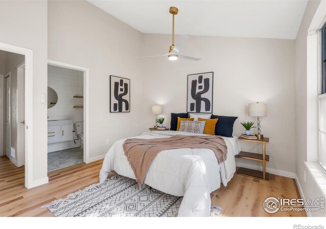 bedroom featuring baseboards, lofted ceiling, ensuite bath, and wood finished floors