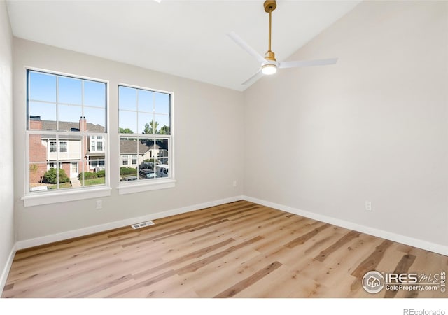 spare room with ceiling fan, wood finished floors, baseboards, and vaulted ceiling