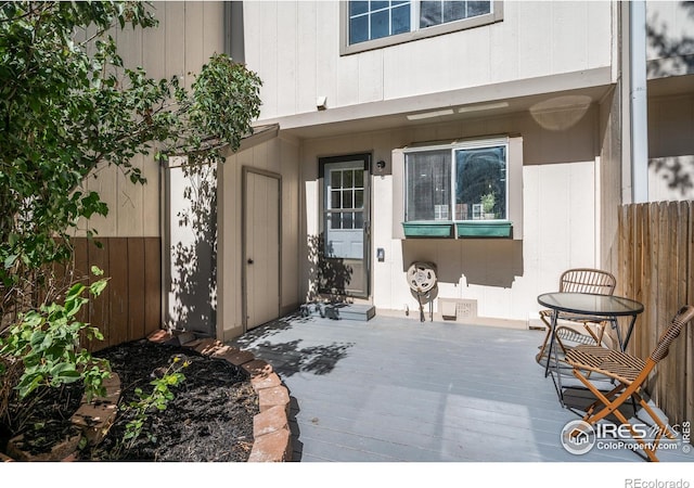 view of exterior entry featuring a wooden deck and fence