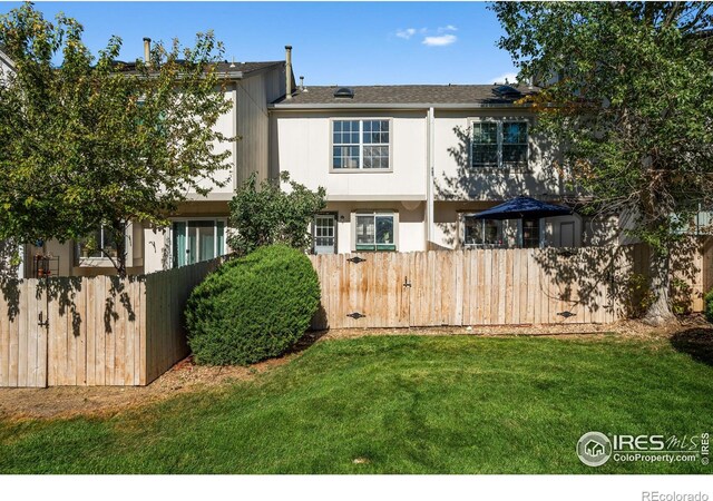 rear view of property with a lawn and fence