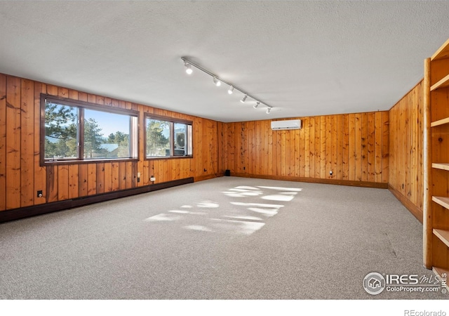 871 E Ln, Estes Park, CO 80517 - unfurnished room featuring wooden walls, track lighting, a wall unit AC, carpet floors, and a textured ceiling