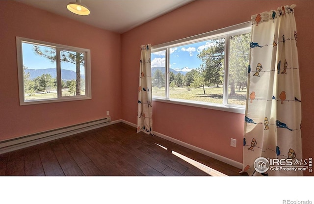 871 E Ln, Estes Park, CO 80517 - empty room featuring a baseboard heating unit, plenty of natural light, baseboards, and wood finished floors