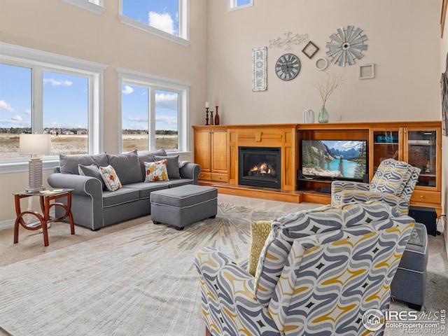 carpeted living room featuring a high ceiling and a glass covered fireplace