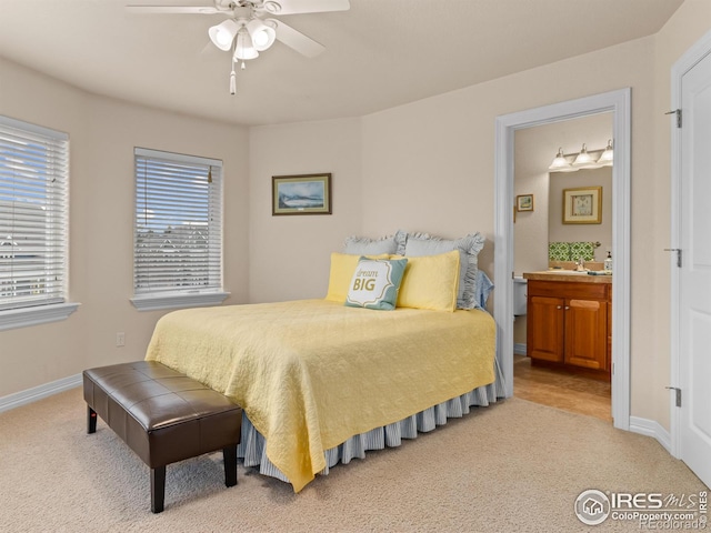 bedroom with light colored carpet, a ceiling fan, ensuite bathroom, and baseboards