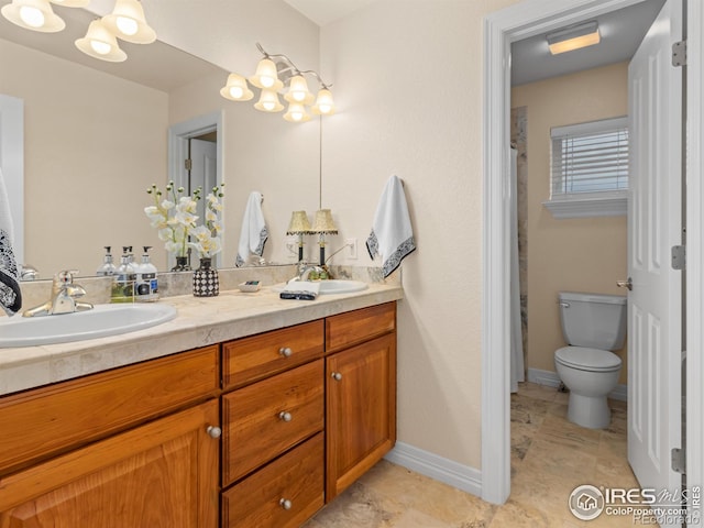 full bathroom with a sink, baseboards, toilet, and double vanity